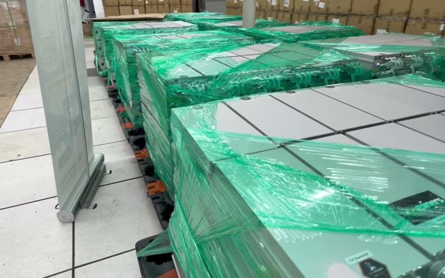Pallets of boxed miners wrapped in green film on the Houston site floor