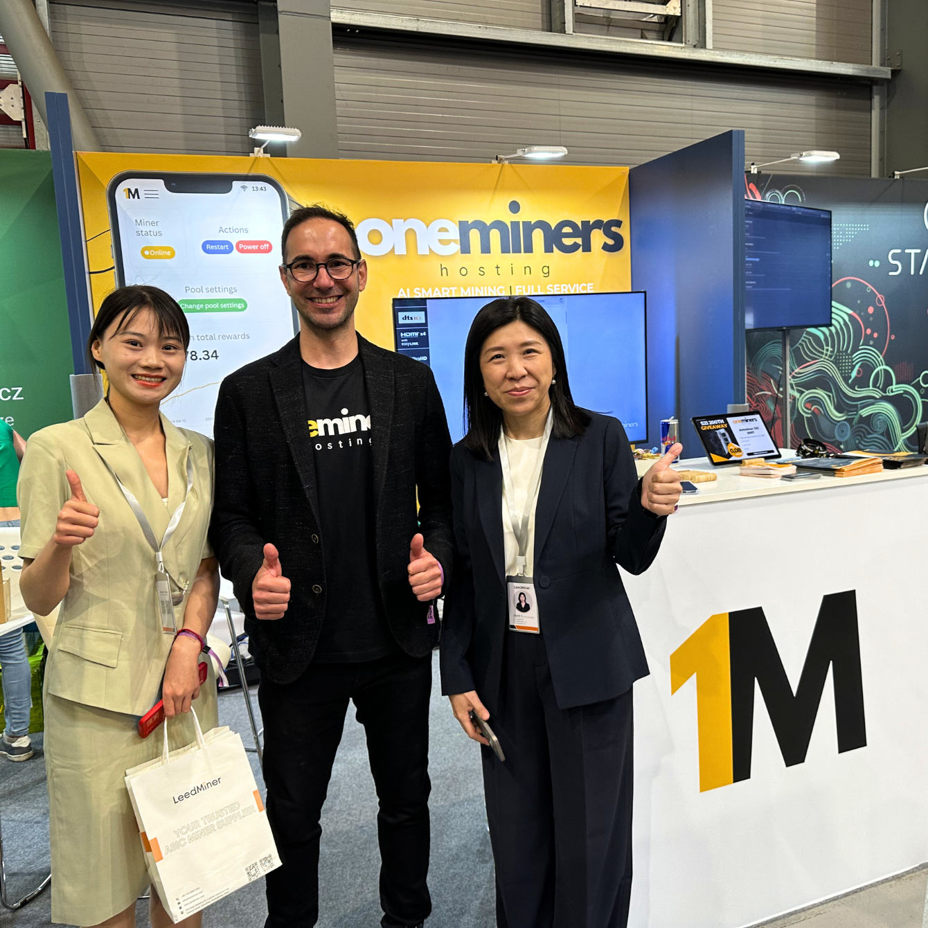 OneMiners CEO with partners in front of the OneMiners booth at a crypto conference