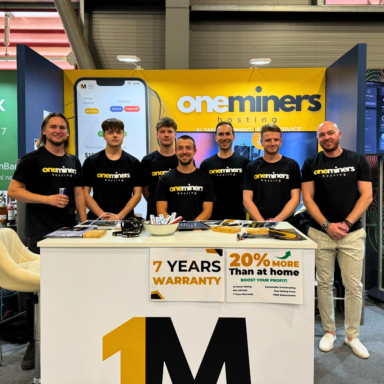 OneMiners team at BTC Prague 2024 booth showcasing crypto mining hosting services.