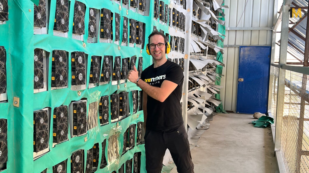 Person standing in front of a wall displaying computer fans in a warehouse setting.
