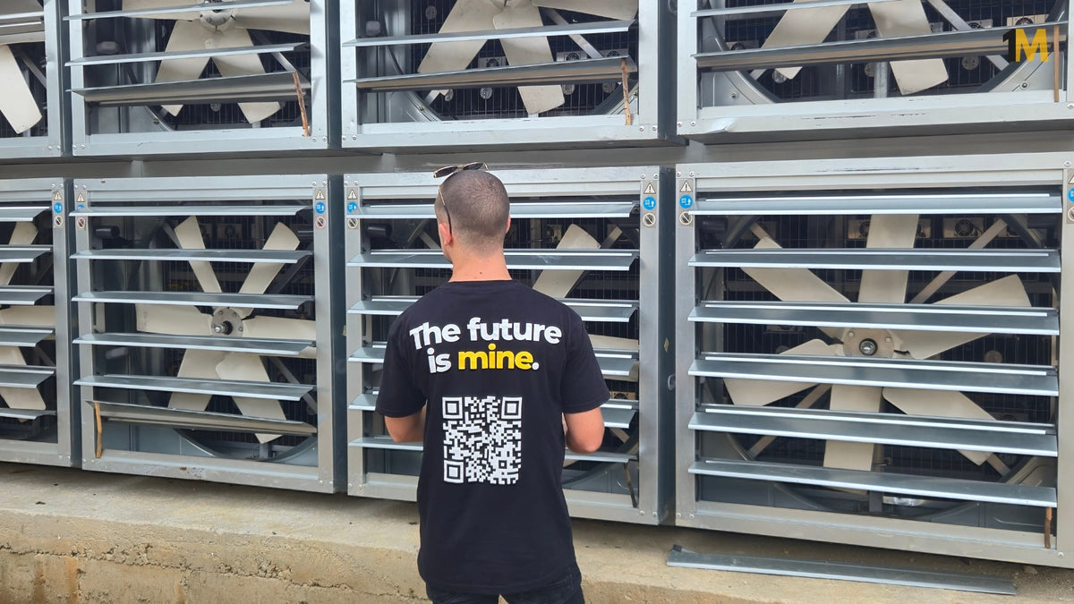Person wearing a black t-shirt with 'The future is mine' text and QR code, standing in front of metal storage units.