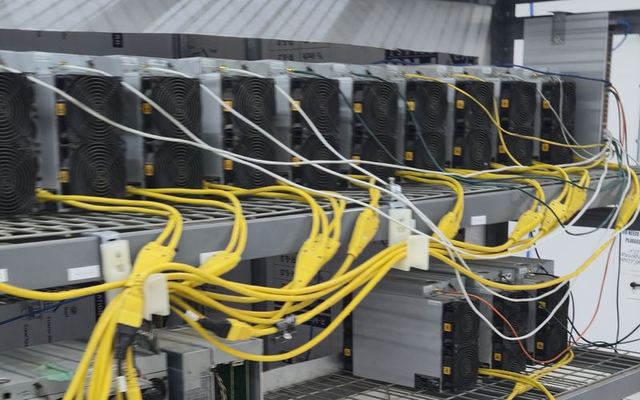 Rows of air-cooled miners on shelving with network cables